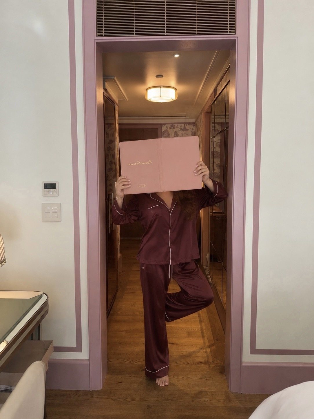 Blair in satin pajamas holding a room service menu